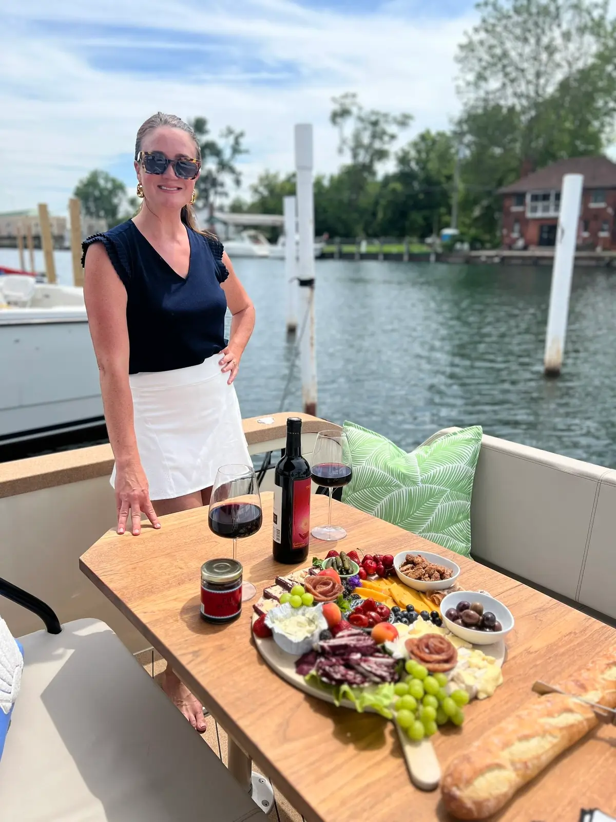 Crew member serving a charcuterie board and wine dockside