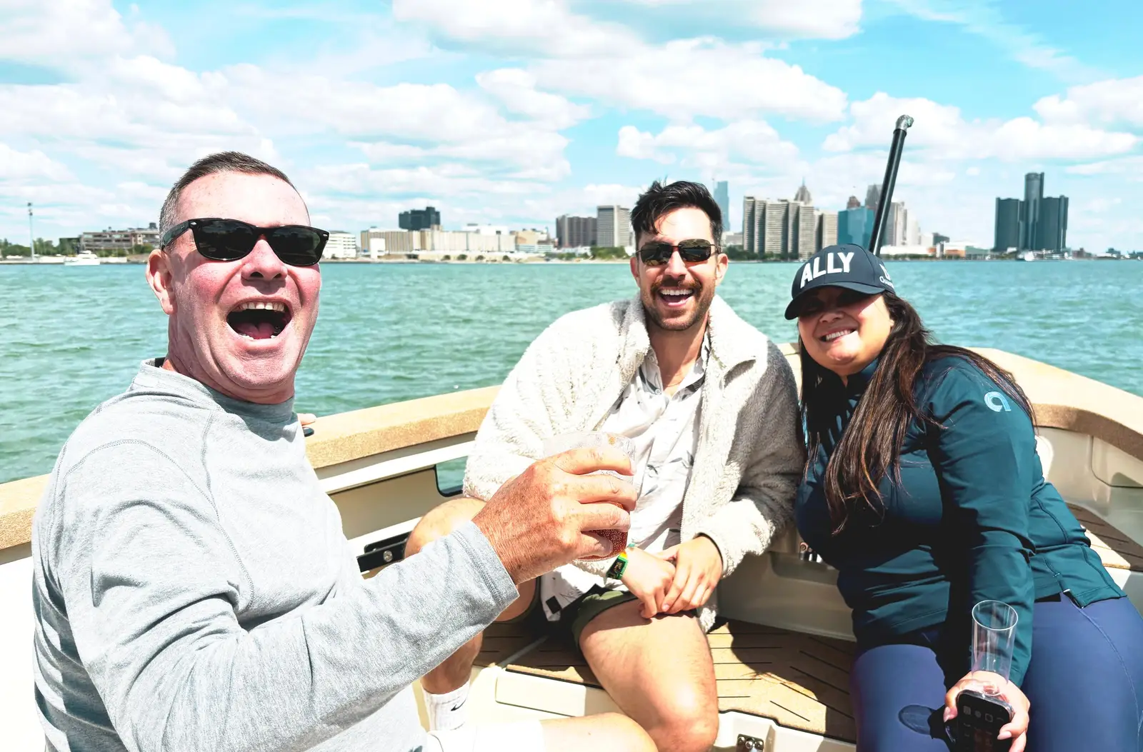 Three friends laughing and cheering aboard the Sycorax with the Detroit skyline behind them